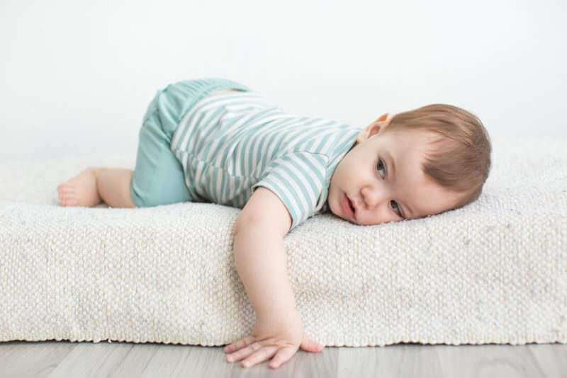 Boys Baby Clothing and Essentials Collection featuring a baby in a striped outfit on a soft surface.
