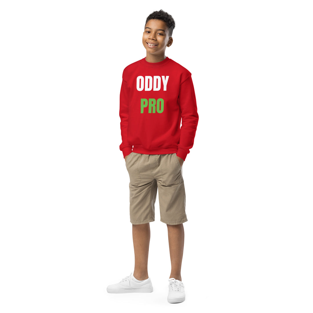 A smiling boy wearing an Oddy Pro Youth crewneck sweatshirt in red with khaki shorts, ideal for casual wear.